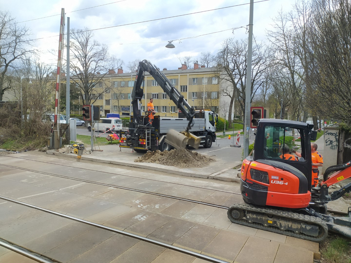 Bauarbeiter und Maschinen von Pfnier & Co GmbH bei der Durchführung von Bauarbeiten an einer Bahnkreuzung in Wien zur Verbesserung der Sicherheit und Infrastruktur.