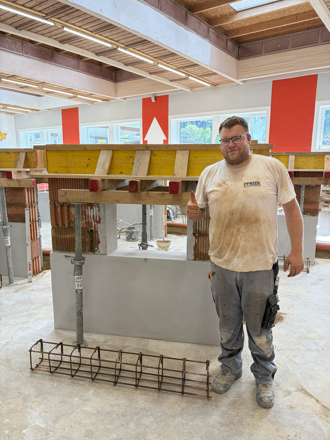 : Tobias Strass steht mit Daumen nach oben neben seiner fertiggestellten Mauerwerkskonstruktion : Tobias Strass steht mit Daumen nach oben neben seiner fertiggestellten Mauerwerkskonstruktion