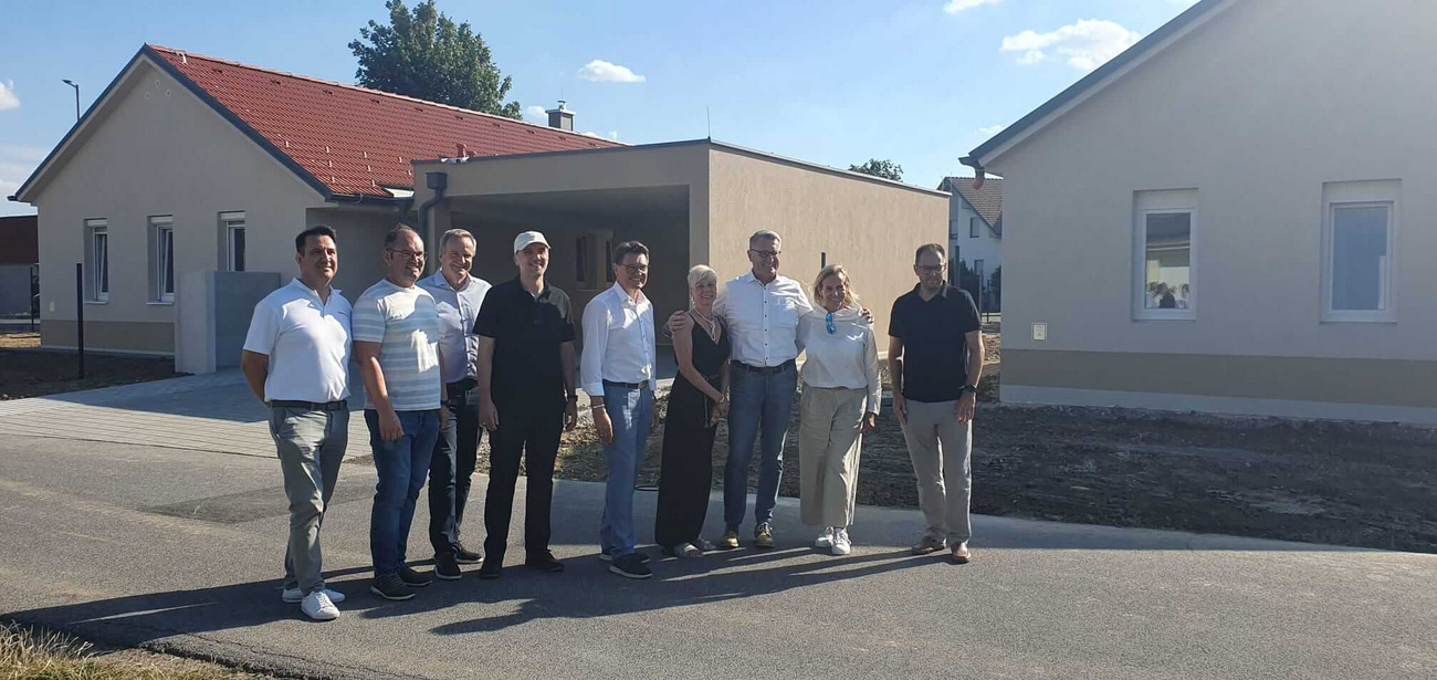 Neun Personen stehen vor neu gebauten Häusern in Niederösterreich.
