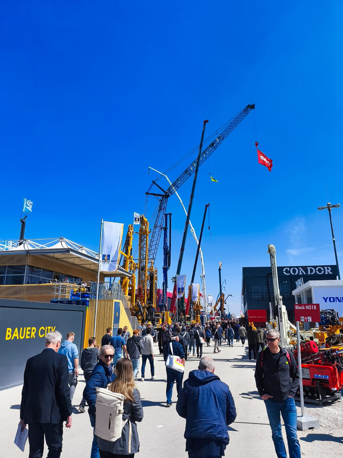 Besuchergruppe auf der BAUMA 2025 zwischen Baugeräten und Messepavillons