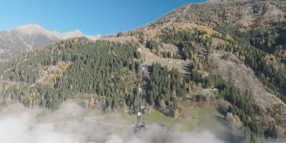Luftaufnahme eines Bergwaldes mit herbstlich gefärbten Bäumen und ehemaliger Bahntrasse